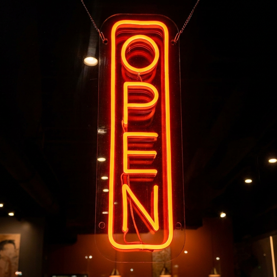 Vertical red neon “OPEN” sign glowing in a dark restaurant window.
